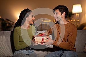 Husband Giving Gift Box To Wife On Christmas At Home