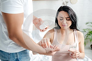 Husband giving pills to pregnant wife with pain