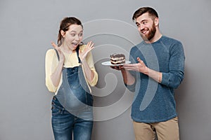 Husband giving plate with chocolae cake to his pregnant wife