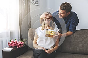 Husband giving romantic surprise gift to beloved wife at home. closed eyes with hand from behind