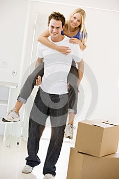 Husband giving wife piggyback in new home smiling