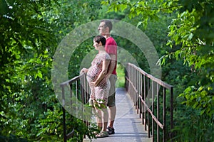 Husband with his pregnant wife on the bridge