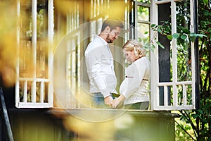 Husband with his pregnant wife on the porch of the house