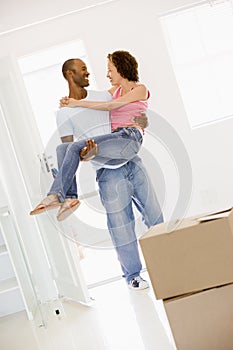 Husband holding wife in new home smiling