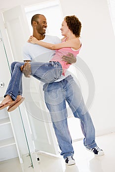 Husband holding wife in new home smiling