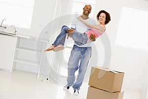 Husband holding wife in new home smiling