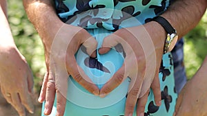 The husband hugs his pregnant wife in the park, close-up.