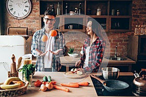 Husband juggles oranges while wife cooking