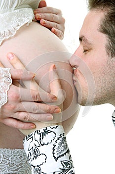 Husband kiss his pregnant wife belly.