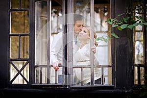 Husband kisses his pregnant wife in the house. View through window