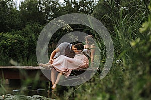 Husband kisses his wife`s belly while relaxing at the lake