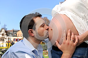 Husband kissing pregnant belly of his wife