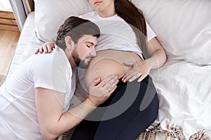 Husband is listening pregnant wife`s tummy