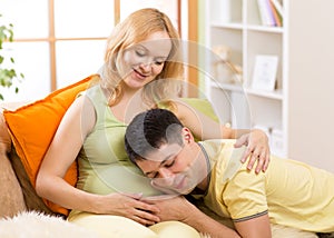 Husband listens to baby heartbeat lying on belly