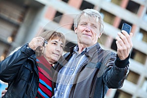 Husband making selfie by phone when wife holding house keys in hand