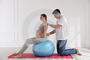 Husband massaging his pregnant wife in room. Preparation for child birth