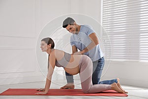 Husband massaging pregnant wife in light room. Preparation for child birth