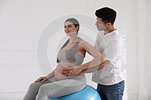 Husband massaging pregnant wife in light room. Preparation for child birth