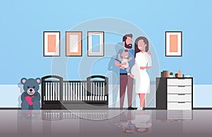 Husband with pregnancy wife holding newborn baby son standing near crib happy family parenthood concept modern baby`s