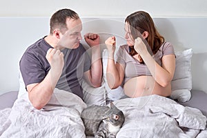 A husband and a pregnant wife quarrel in their home bed. Couple`s fight and aggression during a woman pregnancy