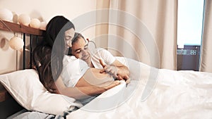 Husband stroking pregnant wife`s belly in bed