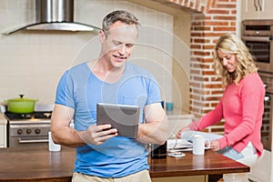 Husband using tablet while wife having breakfast