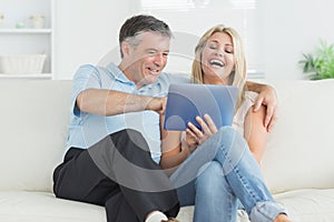 Husband and wife laughing at tablet pc