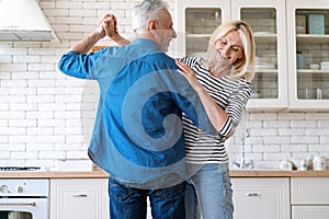 Husband and wife listening music, dancing and enjoying moment in kitchen