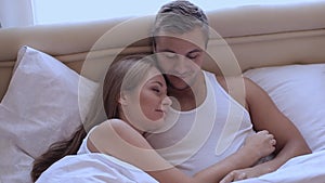 Husband and wife lying in bed in an embrace