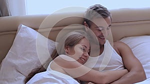 Husband and wife lying in bed in an embrace