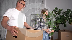 Husband and wife, a mature couple bring boxes of things and an indoor flower into their new home. Relocation and real