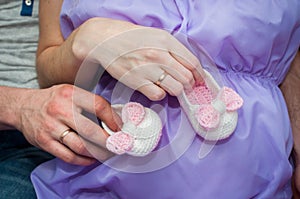 The husband and wife, mom and dad hold hands with booties on the belly.pregnancy