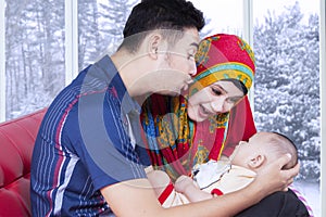 Husband and wife playing with baby on couch