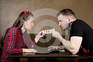 Husband and wife are pulling money at each other, angrily looking
