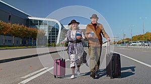 Husband wife retirees tourists go to airport terminal for boarding with luggage, tickets, passports