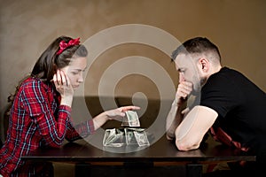 Husband and wife are sadly looking at the remaining money, sitting at a table