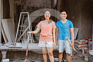 Husband and wife with shovel and cup standing near raw materials