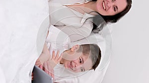 Husband wife and son laugh a lot funny joke bed holiday look at tablet communicate conversation love at home happiness