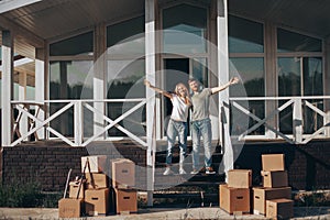 Husband and wife standing in front of new buying home with boxes