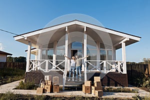 Husband and wife standing in front of new buying home with boxes