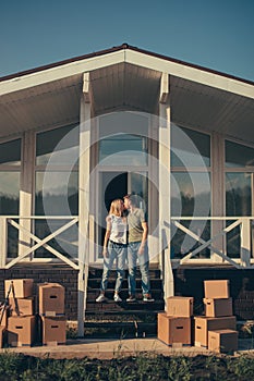 Husband and wife standing in front of new buying home with boxes