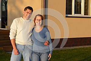 Husband and wife standing near house