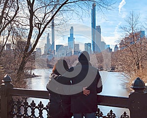 Husband and wife standing on the Old Bridge viewing the skyline of New York City across the Bank Rock Bay.