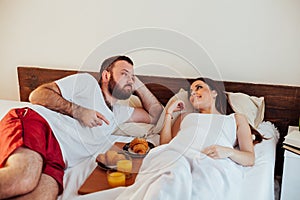 Husband and wife wake up in the morning in the bedroom weekend breakfast in bed