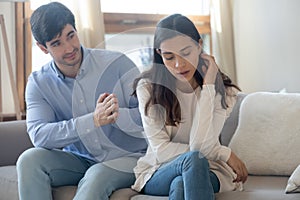 Husband of young woman clasping hands asking forgiveness after quarrel