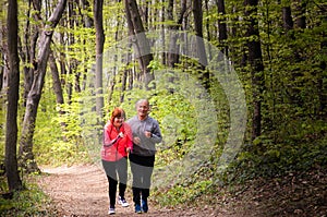 Husbanf and wife wearing sportswear and running in forest