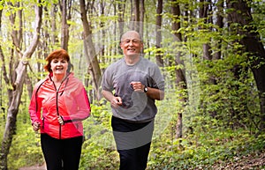 Husbanf and wife wearing sportswear and running in forest