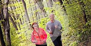 Husbanf and wife wearing sportswear and running in forest