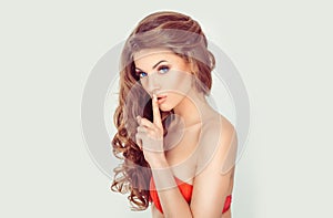 Hush. Woman wide eyed asking for silence or secrecy with finger on lips shh hand gesture white background wall. Pretty girl photo