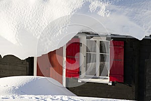 Hut with red shutters in deep snow